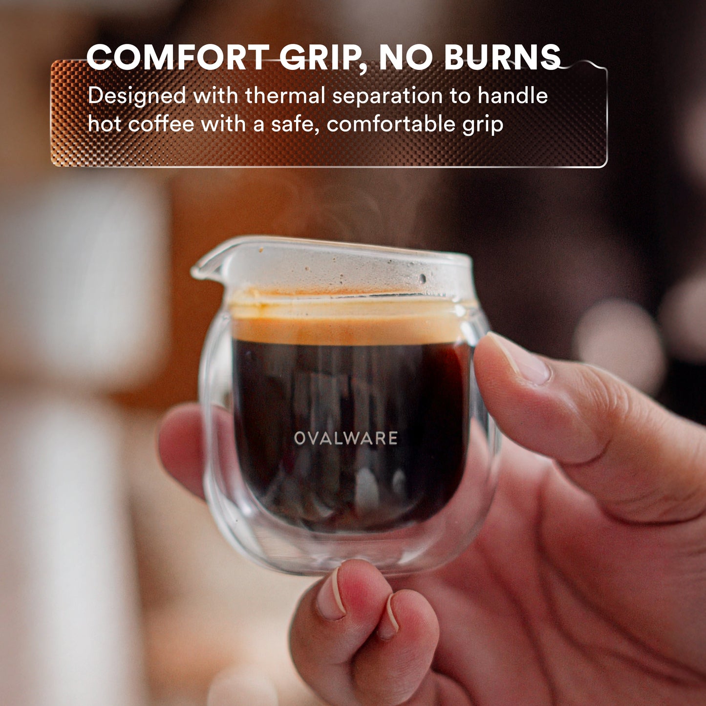 Hand holding a clear coffee cup with steam, featuring text about comfort grip and thermal separation.